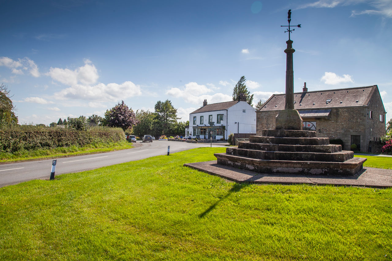 weather vane set on stone steps on village green